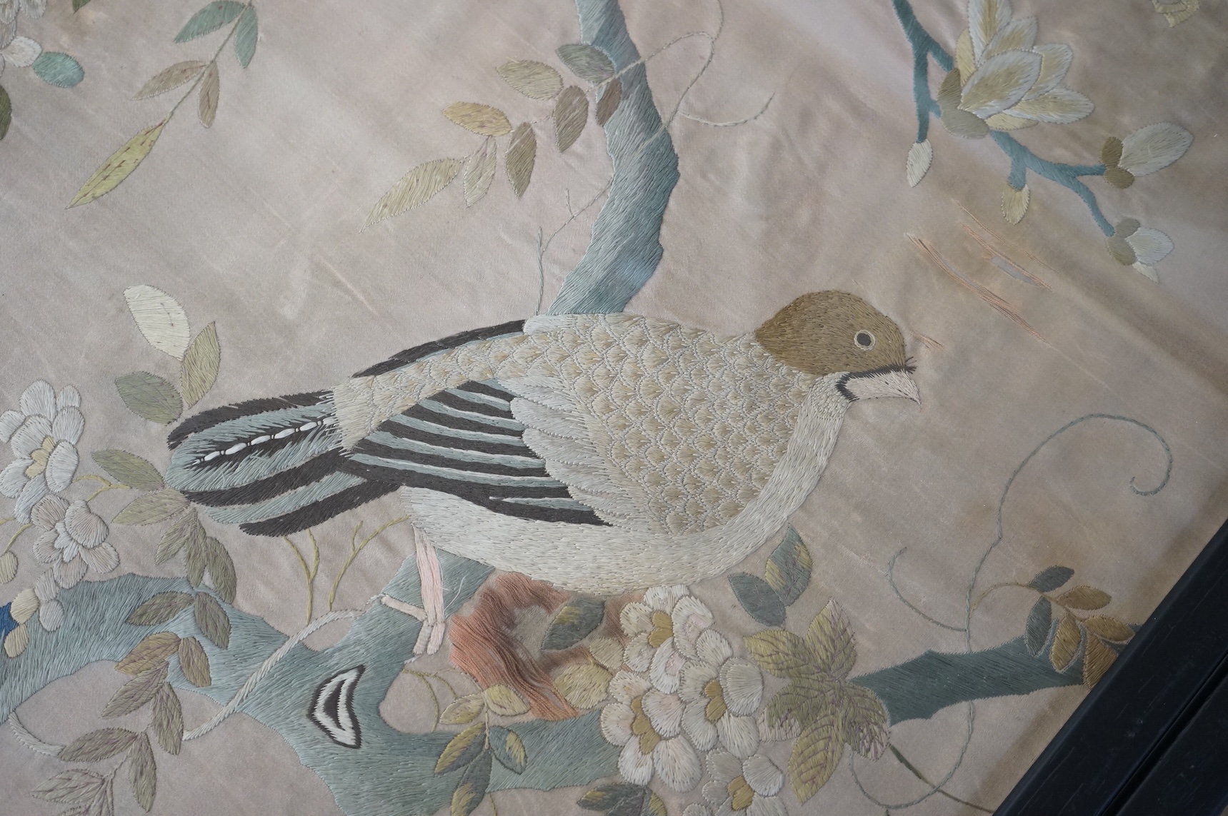 A pair of framed 19th century Chinese silk embroideries of exotic birds amongst entwined flowering branches, embroidered on a beige silk back ground, possibly cut from a larger embroidery. 47cm x 57cm., Condition - one f
